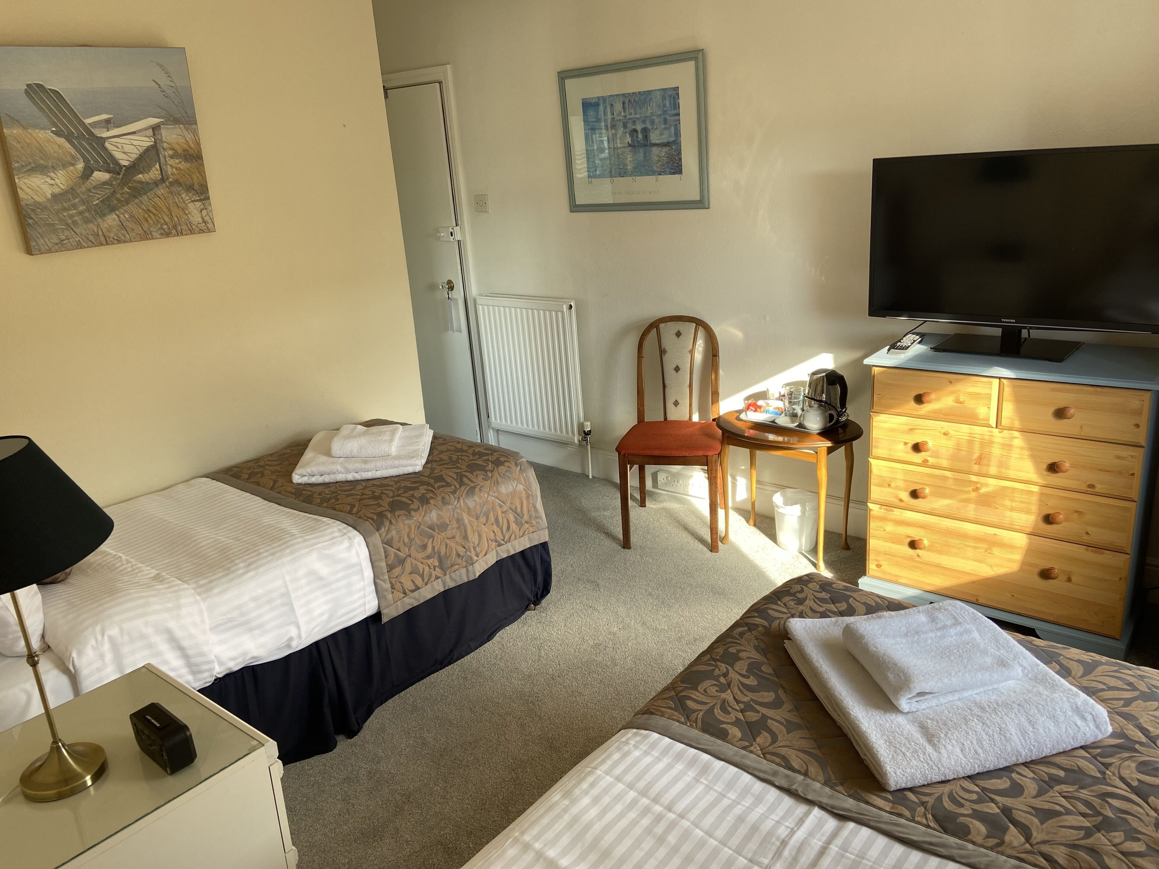 Ein Hotelzimmer mit zwei Betten, einem Fernseher, einem Schminktisch und einem Sessel.