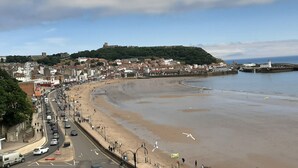 A coastal town with a beach, a historic hilltop, and a sea wall.