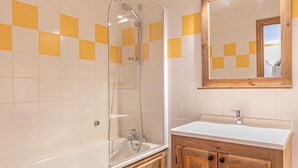 A bathroom with a bathtub, a wooden vanity, and a mirror with lights. - 300m from ski slopes, floor -2, balcony, tv, 50m², Aussois (Aussois)