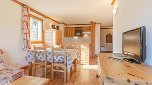 A cozy cabin-style room with a wooden dining table, chairs, a television, and a kitchen area with wooden cabinets and a microwave. - 300m from ski slopes, floor -2, balcony, tv, 50m², Aussois (Aussois)