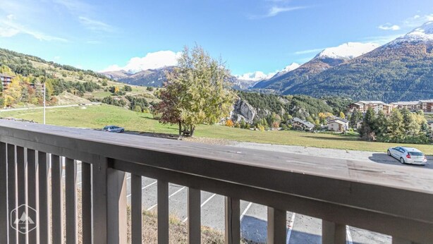 A scenic view from a balcony overlooking a road with cars, a tree, and a mountain range in the background. - 300m from ski slopes, floor -2, balcony, tv, 50m², Aussois (Aussois)