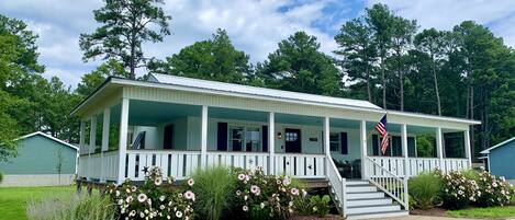 A white wooden house with a porch, a flag, and a number 5329 on the front.