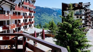 A multi-story hotel with balconies, a wooden deck, and a mountain view.