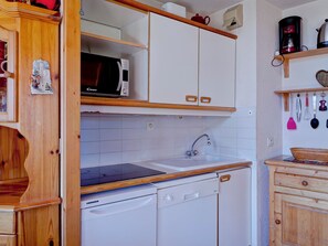 A kitchen with white cabinets, a microwave, a sink, and a dishwasher.