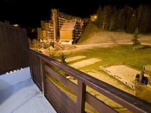 Une vue nocturne dâun hĂŽtel composĂ© de plusieurs bĂątiments, avec un espace verdoyant et une terrasse en bois.