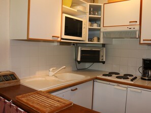 Eine Küche mit Mikrowelle, Backofen, Spüle und einem Holzer Schneidebrett.