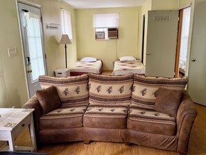 A room with a brown sofa, two beds with patterned quilts, a lamp, and a wardrobe. - Close to Tippy Dam, Lake Elinor, Dickson Park. Clean & cozy! (Brethren)
