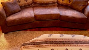 Ein braunes Ledersofa mit gemusterten Kissen und passendem Hocker.