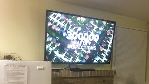 Ein Wohnzimmer mit Flachbildfernseher über einem Kamin aus Ziegelsteinen, einem Kühlschrank und einem kleinen Tisch mit Stuhl.