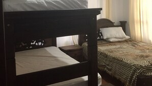 A room with a bunk bed and a single bed, wooden beams on the ceiling, a patterned bedspread, and a window with curtains. - Hotel Duna Campestre (Sáchica)