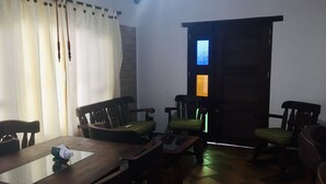 A dining area with a wooden table and chairs, a window with curtains, and a door with a stained glass window. - Hotel Duna Campestre (Sáchica)
