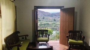 A room with a sofa, two chairs, and a view of a mountainous landscape through an open door. - Hotel Duna Campestre (Sáchica)