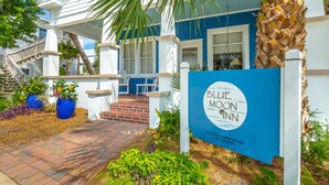 A Blue Moon Inn with a white and blue exterior, a covered porch, and a brick pathway leading to the entrance. - Heart of Historic Apalachicola, Nostalgic Florida “Blue Moon Cottage ” (Apalachicola)