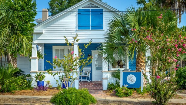 A two-story house with a blue and white exterior, a front porch with a bench, and a sign indicating it is a Blue Moon Inn. - Heart of Historic Apalachicola, Nostalgic Florida “Blue Moon Cottage  ” (Apalachicola)