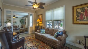 A living room with a brown leather sofa, patterned rug, and a ceiling fan. - Heart of Historic Apalachicola, Nostalgic Florida “Blue Moon Cottage ” (Apalachicola)