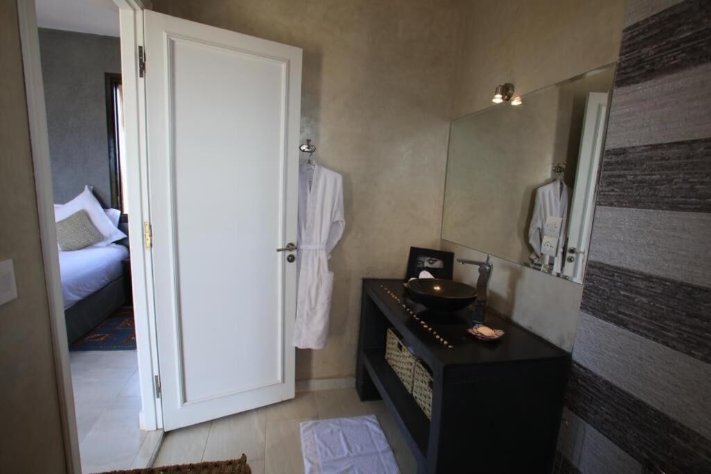 A bathroom with a white door, a black vanity with a mirror, and a towel on the floor.