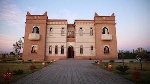 Ein großes, symmetrisches Gebäude mit einem zentralen Eingang, Bogenfenstern und einem gepflasterten Innenhof.