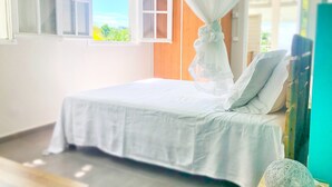 A bedroom with a bed, a window, and a curtain. - Studio Grande Anse Residence "O Coeur de Deshaies". Incredible seaview. (Deshaies)