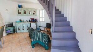 A kitchen with a microwave, toaster, and cabinets. There is a staircase with a handrail.