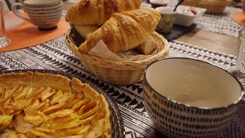 Una mesa con un pastel, cruasanes y un bol.