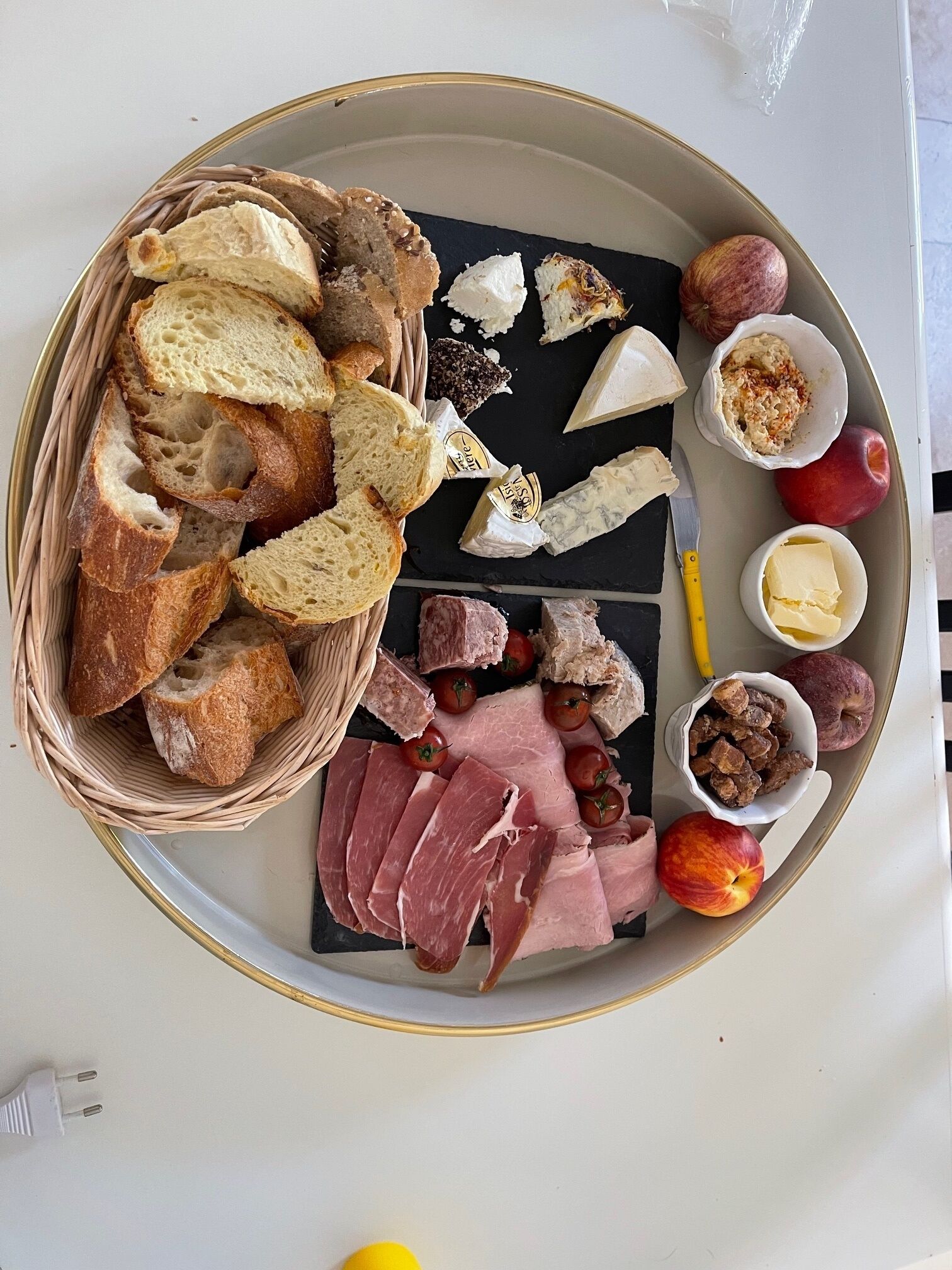 Una bandeja con diversos alimentos, como pan, queso, jamón y frutas.