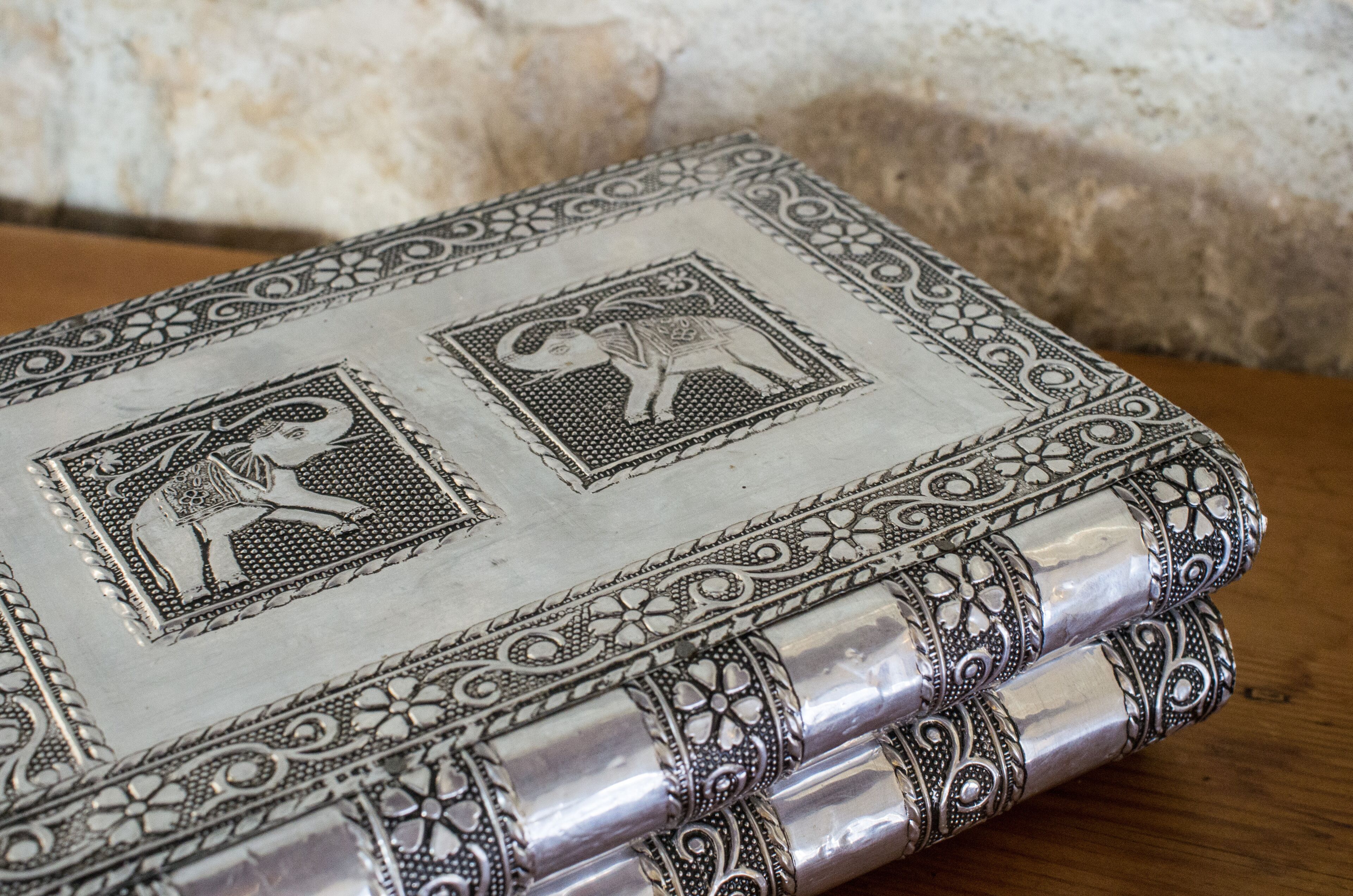 A detailed view of a book with ornate silver edges and intricate designs, featuring two stamps with animal illustrations.