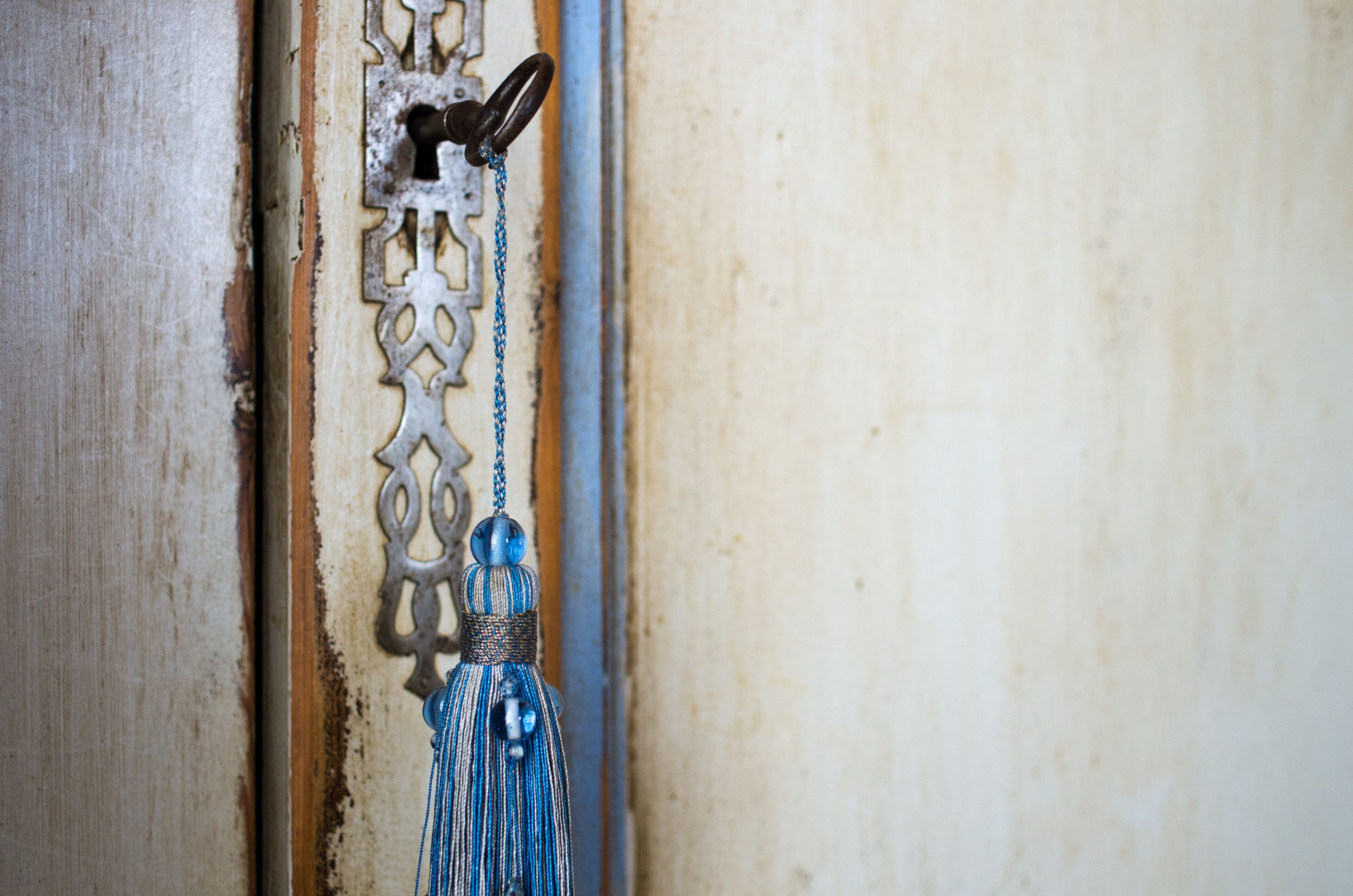 Una puerta con una aldaba metálica decorativa y un flequillo azul colgando.