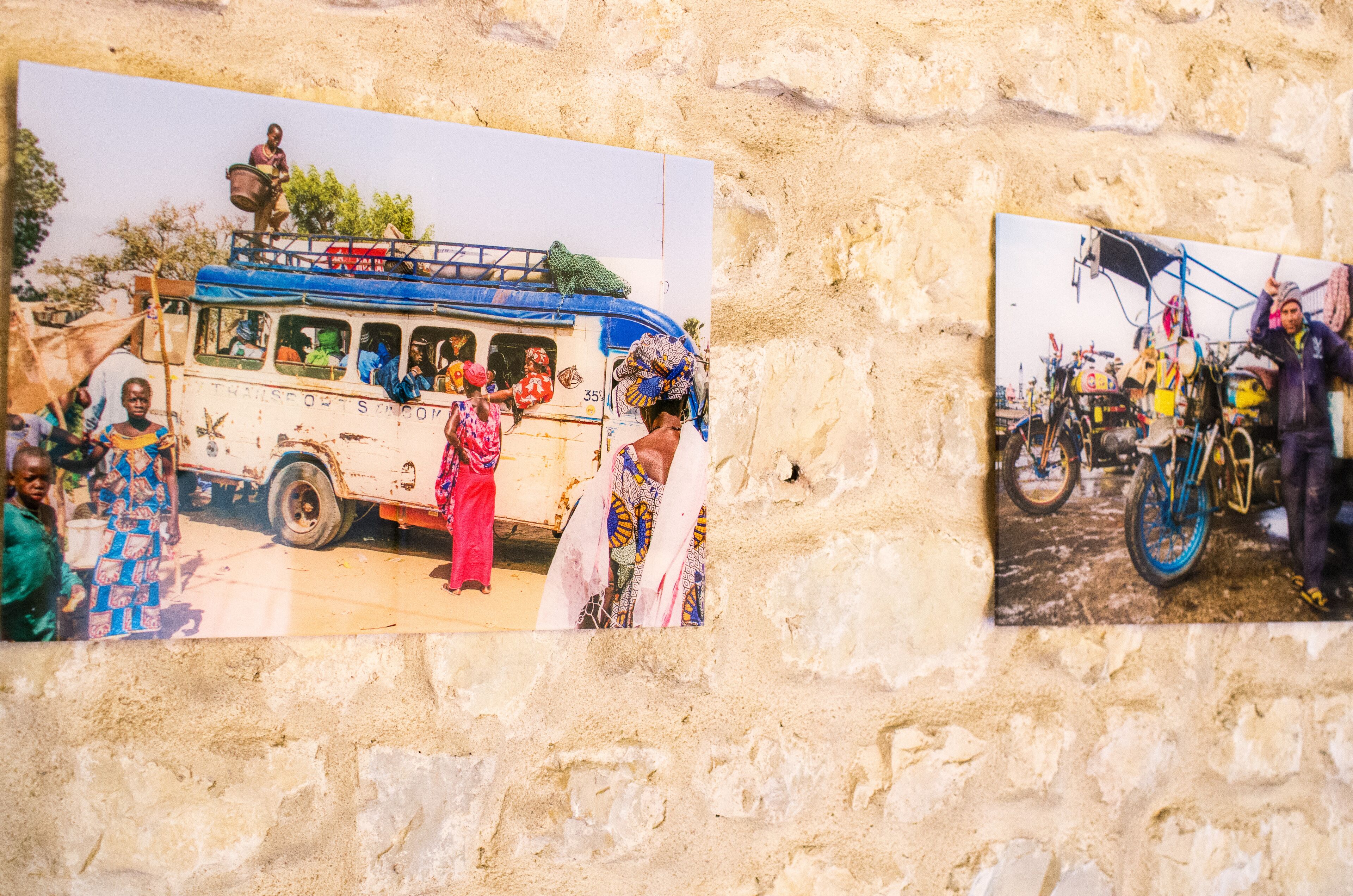 Een muur met twee foto’s: één toont een bus met passagiers en de andere een fiets.