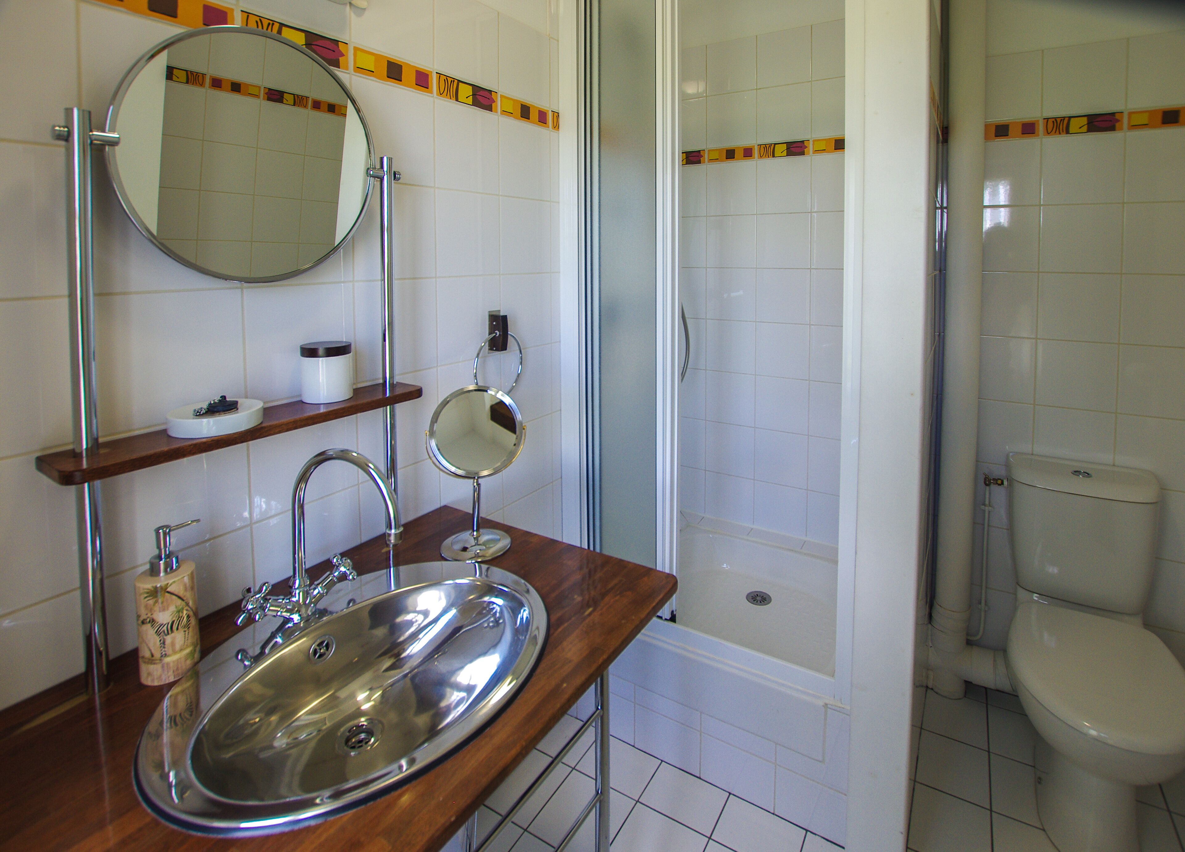 A bathroom with a sink, mirror, shower, and toilet.