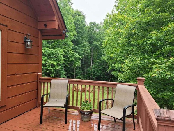 A wooden deck with two chairs and a potted plant.