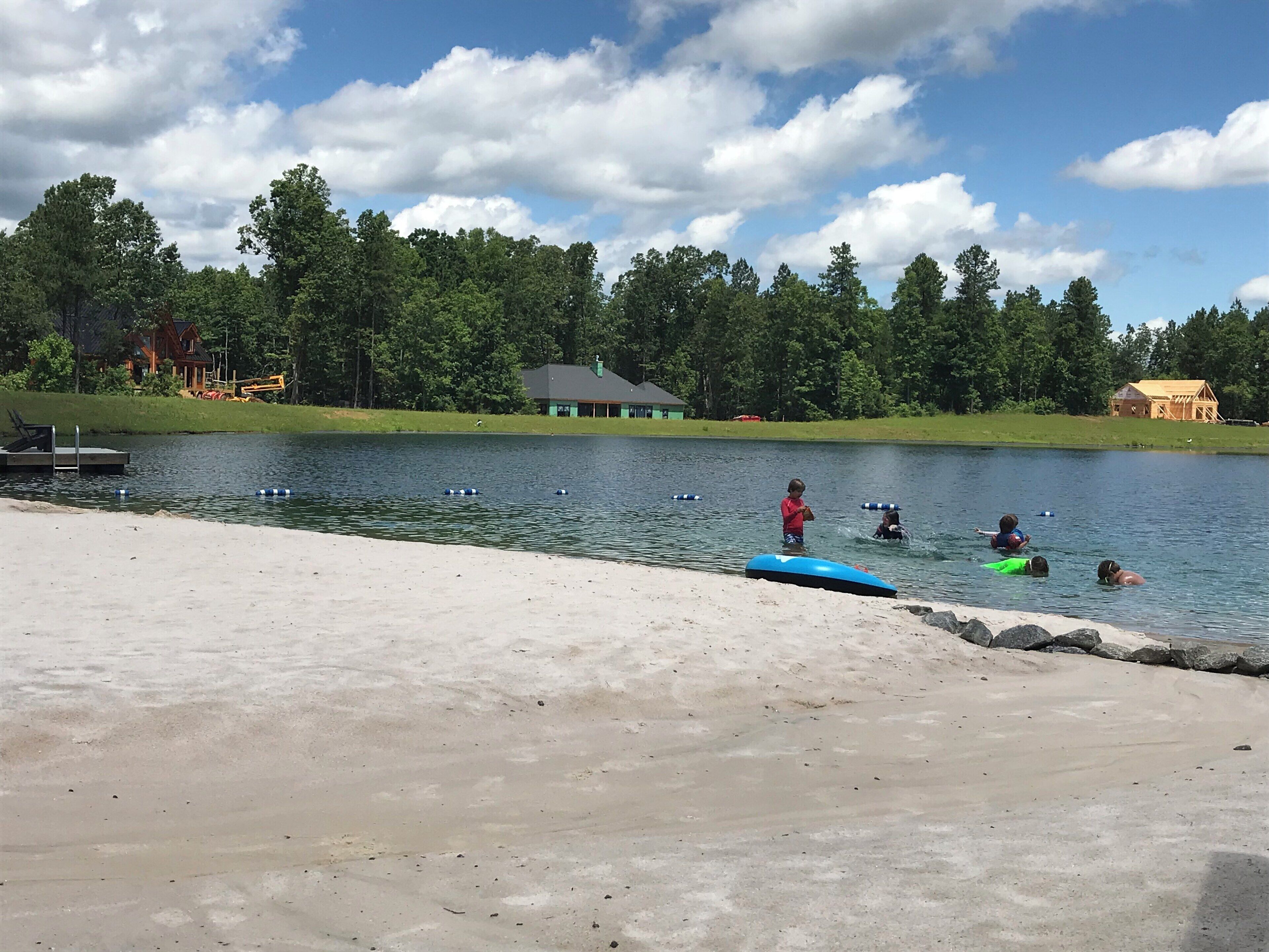 A lakeside scene with a concrete dock, a small house, and a forest in the background.