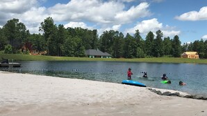 A lakeside scene with a concrete dock, a small house, and a forest in the background. - Peaceful Blue Ridge Mountain Retreat Near Marion, NC (Nebo)