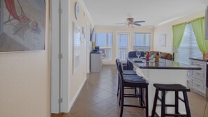 Une cuisine dotée d’un îlot central, de tabourets de bar, d’un ventilateur de plafond et donnant sur un balcon.