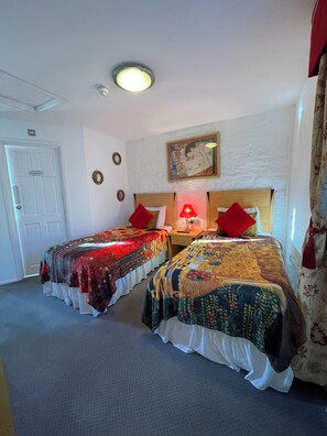 A hotel room with two beds, a painting on the wall, a ceiling light, and a door labeled "Bathroom". - The Old Station Inn (Bristol)