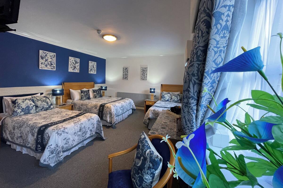 A hotel room with two beds, a sitting area, and a view of the outdoors.
