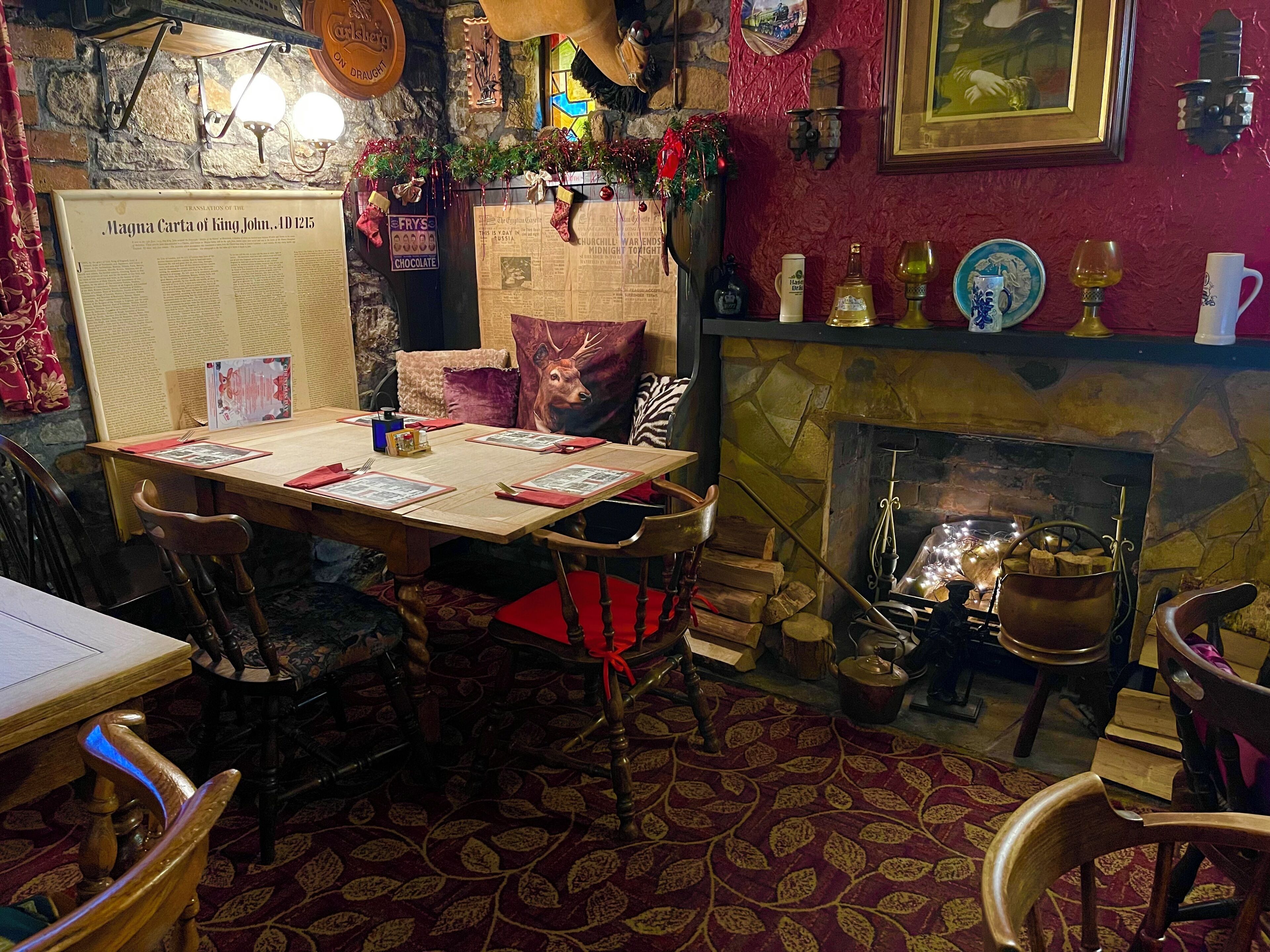 A cozy dining area with a stone fireplace, wooden chairs, and a table set for a meal.