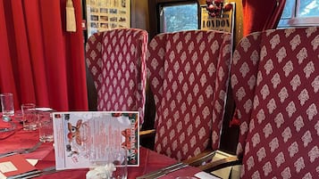 Un comedor con manteles rojos, sillas estampadas y un atril para el menú.