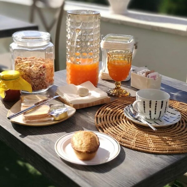 A breakfast setup with cereal, orange juice, and a muffin on a wooden table. - Don Franco (Adelfia)