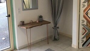Een kamer met een houten console, een spiegel, een grijs gordijn en een behang met patroon.