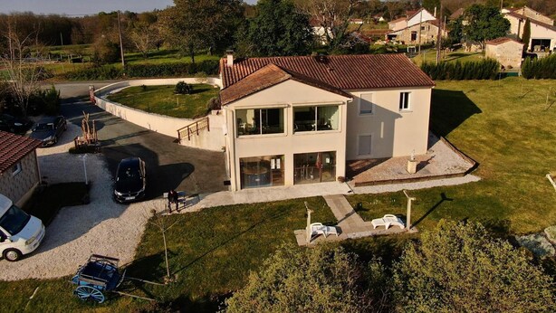 Een twee verdiepingen tellend huis met oprit, garage en een kleine tuin.