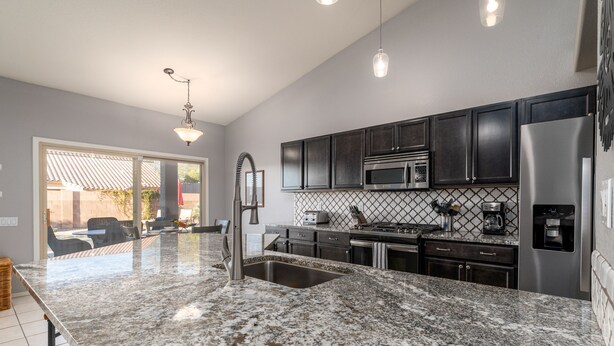 A modern kitchen with granite countertops, stainless steel appliances, and dark cabinetry. - Mystic Mirage is truly a desert oasis with pool and mountain views. (Tucson)