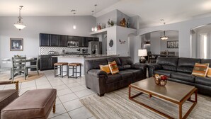 A modern living room with a gray sofa, a wooden coffee table, and a kitchen area in the background. - Mystic Mirage is truly a desert oasis with pool and mountain views. (Tucson)