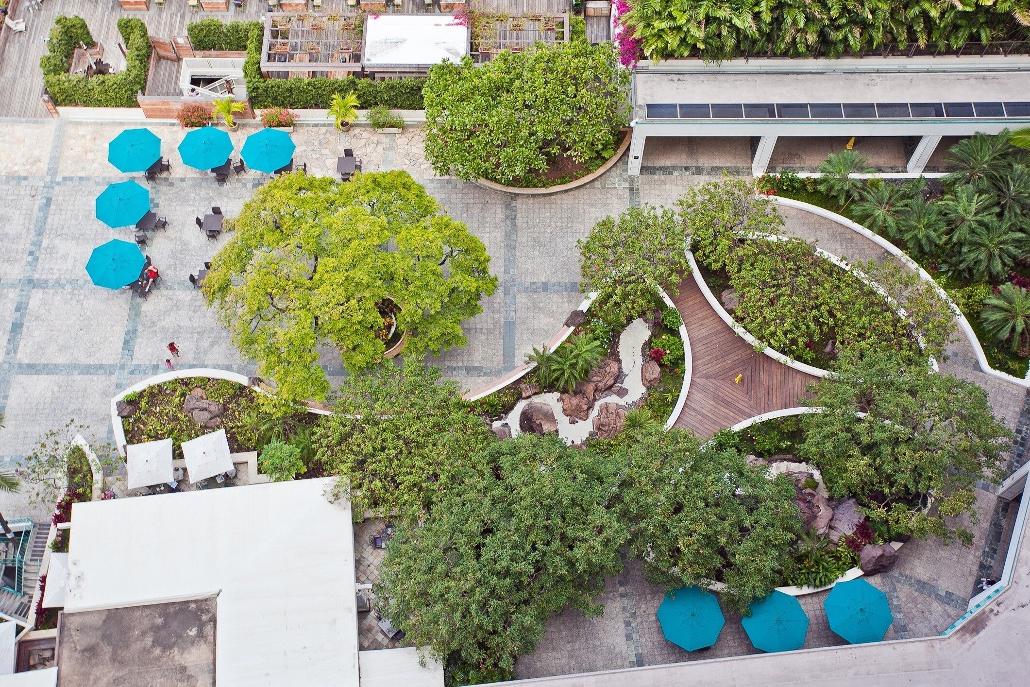 An aerial view of a courtyard with outdoor seating, surrounded by lush greenery and trees.