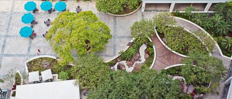 An aerial view of a courtyard with outdoor seating, surrounded by lush greenery and trees.