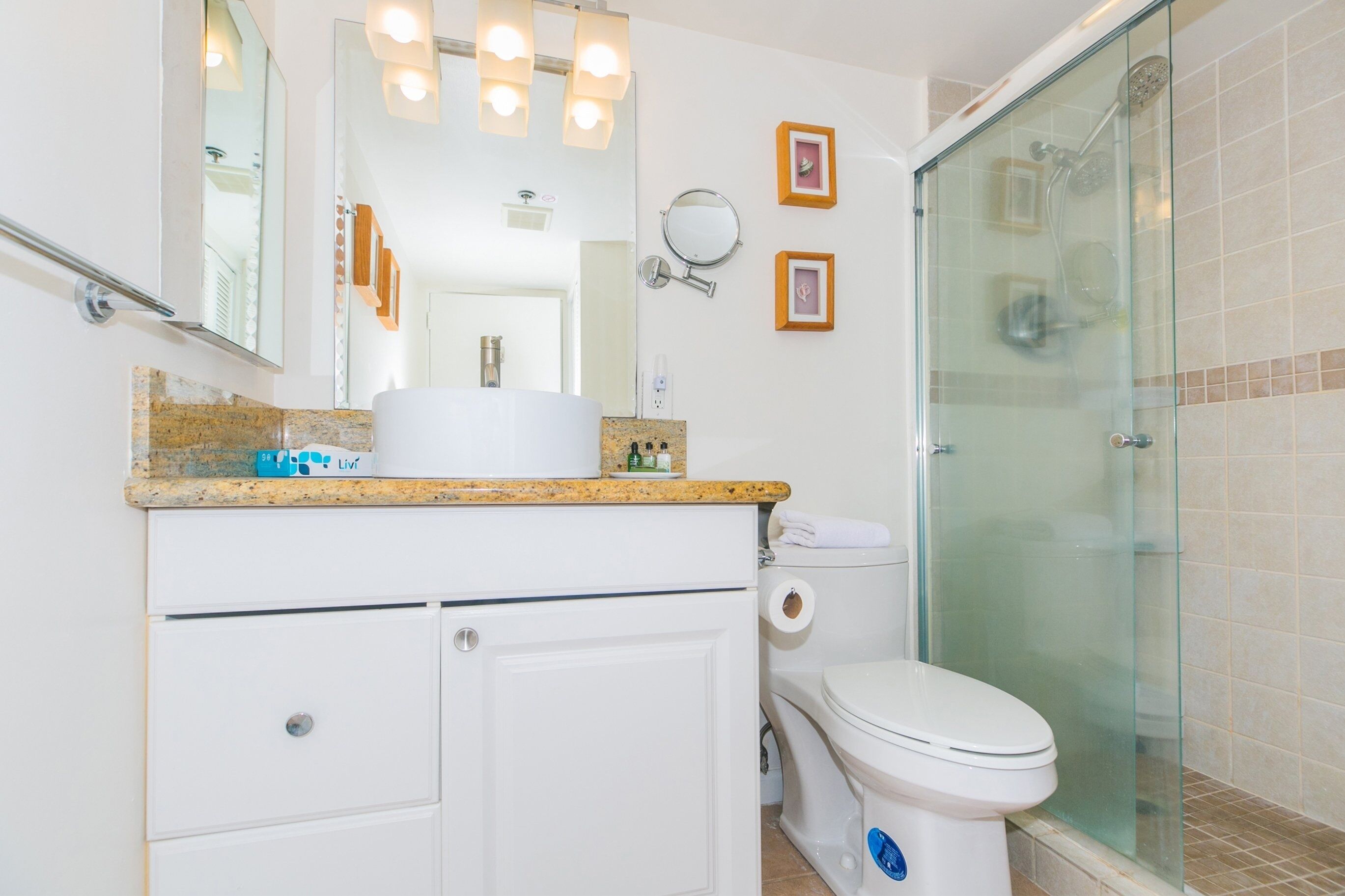 A bathroom with a toilet, a sink with a mirror, and a glass shower enclosure.