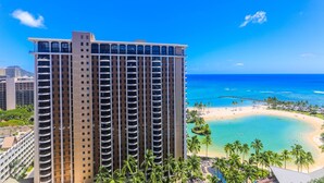 A high-rise hotel with multiple balconies overlooking a beach and ocean.