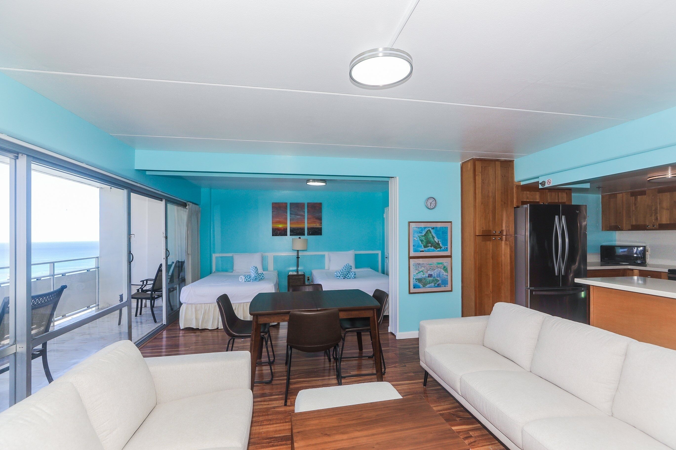 A modern room with a balcony, a dining area, and a kitchenette.