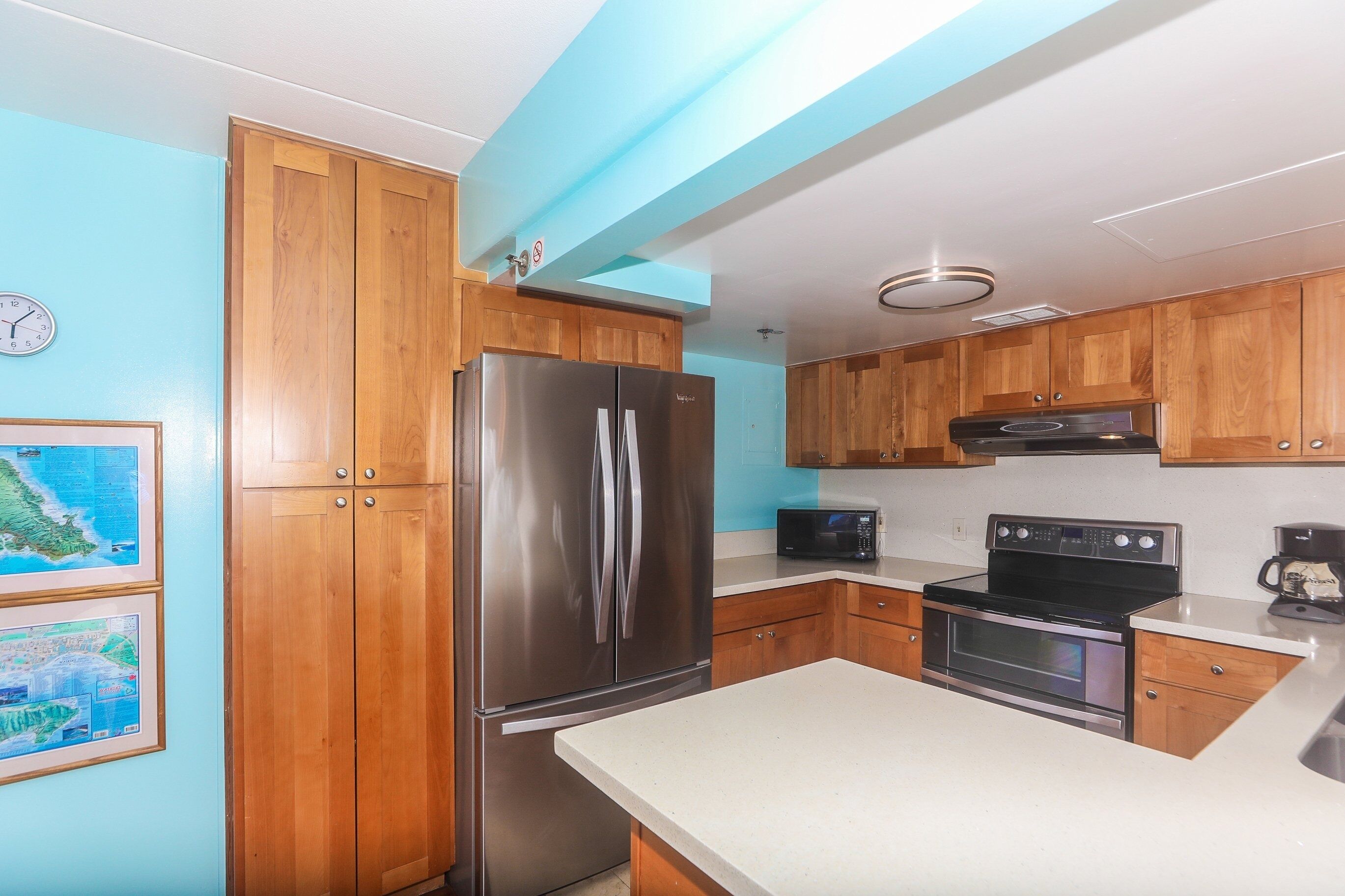 A kitchen with wooden cabinets, a stainless steel refrigerator, a microwave, and an oven.