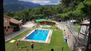 A swimming pool surrounded by a fenced area with a small building in the background. - Camping Repòs del Pedraforca (Saldes)