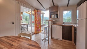 Eine moderne Küche mit Holztisch, Barhocker, Geschirrspüler und Blick ins Freie.